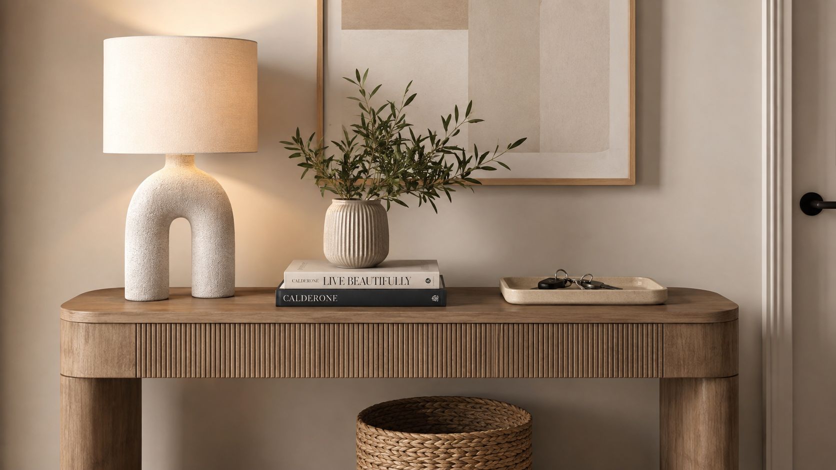 A modern wooden console table with an arched lamp, decorative books, a vase, and a key tray.